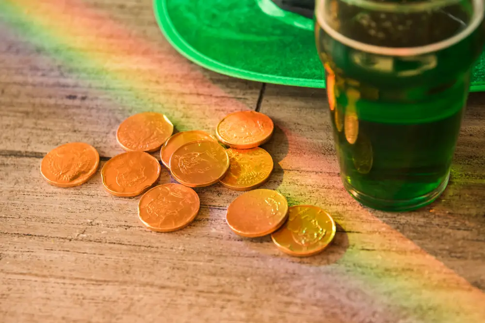 Irish currency on a table next to a green beer, showing details of money in Ireland in a festive and traditional way.