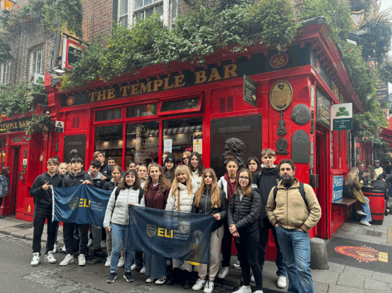 Un grupo numeroso de estudiantes posa frente a la fachada roja y emblemática de The Temple Bar en Dublín. Estudiantes que aprenden los adjetivos en inglés durante su estancia en Irlanda.